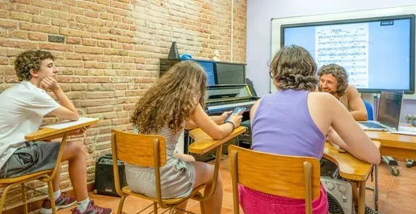 Classe en una aula de l’escola amb un piano i una pantalla digital