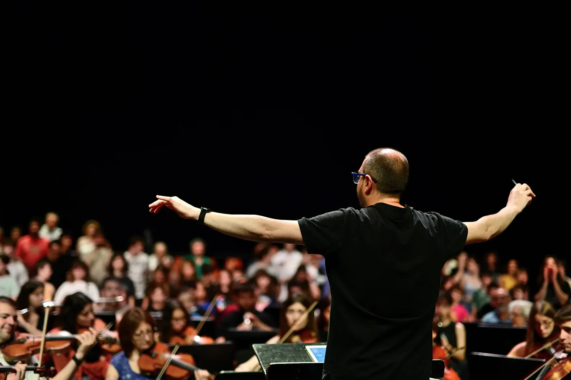 Un director dirigeix una orquestra d’alumnes davant del públic