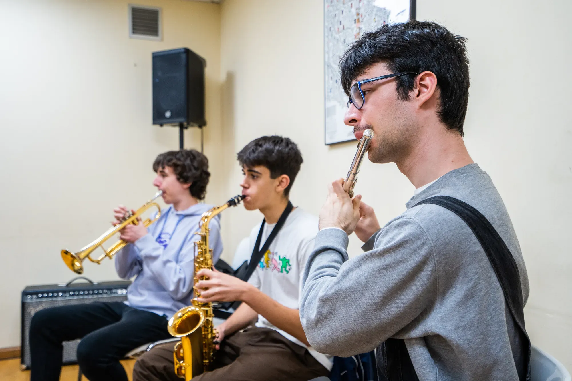 Joves tocant la trompeta, el saxo i la flauta en un assaig